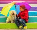 Kind mit seinem Hund unter einem Regenschirm